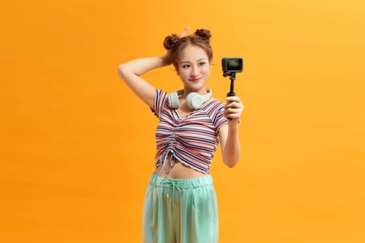 Young woman selfie action cam enjoy over yellow background