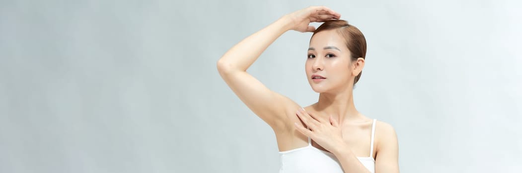 Young Asian woman lifting hands up to show off clean and hygienic armpits or underarms. Banner