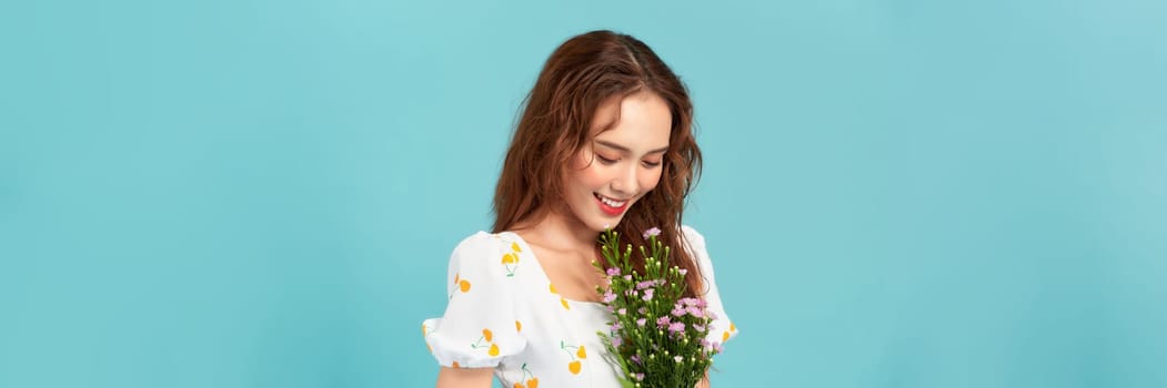 Beautiful cheerful young girl wearing summer dress, holding bouquet of wildflowers