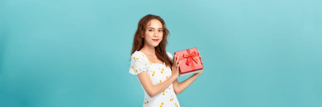 Portrait of happy charismatic girl shaking gift box wondering whats inside as celebrating birthday