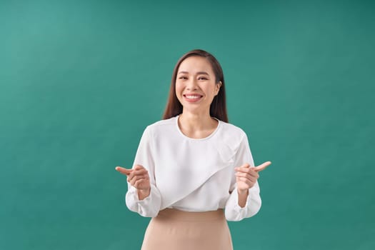 Beautiful young woman in dress pointing fingers sideways, show two ways, giving choice and smiling