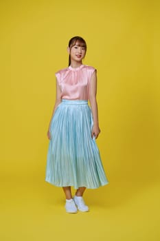 Full length image of young Asian woman wearing trendy dress on pink background