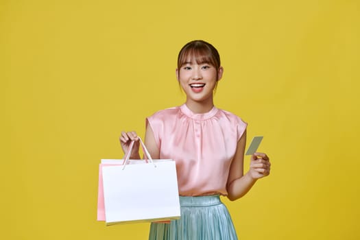 Asian happy female woman girl holds colourful shopping packages and cashless credit card payment
