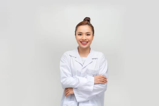 Happy young woman in lab coat on light grey background