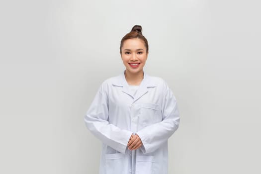 Happy young female doctor in medical uniform smiling while standing with folded arms