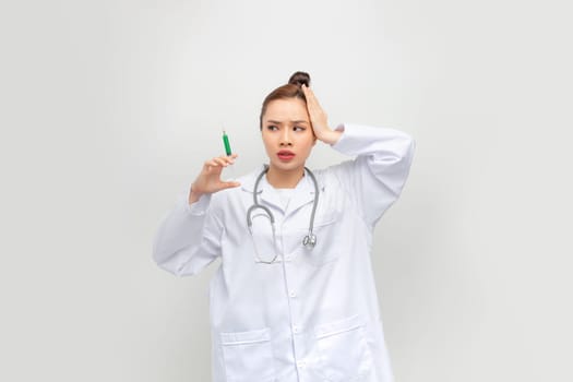 Asian woman with braids holding syringe stressed and frustrated with hand on head