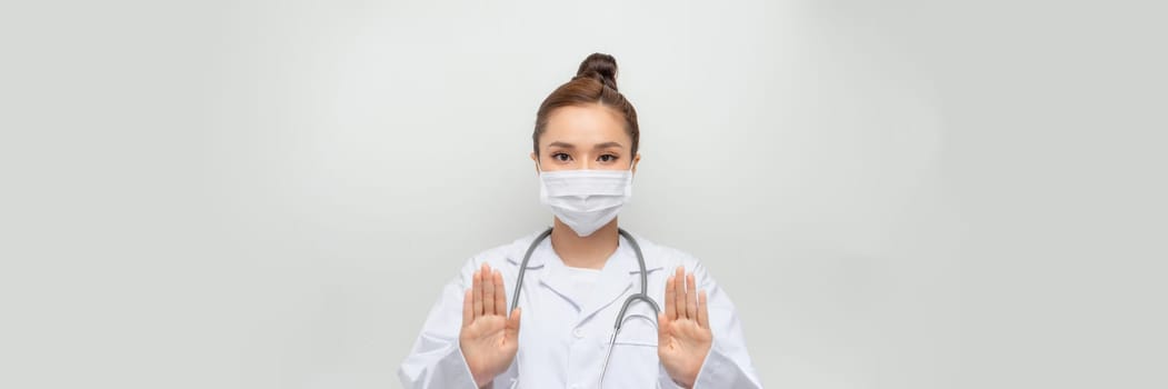 beauty female doctor in coat showing stop hand gesture
