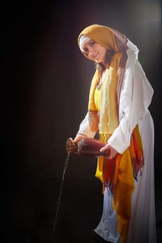 A girl or young woman from ancient Israel, Palestine, Iran, Iraq with a clay jug. A biblical story with Rebekah and water. Stylized photo shoot with a model in Middle Eastern clothes