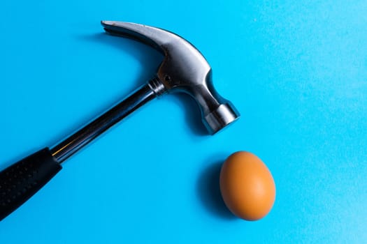 Hammer is hitting on egg with blue background. minimal idea creative concept.