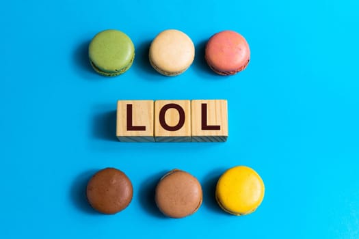 Colorful cake macaron or macaroon on a blue background. Flat lay, top view, copy space. Word Lol