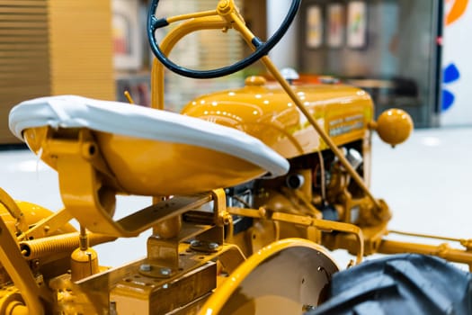 Small yellow tractor in an exhibition, closeup details, wheels