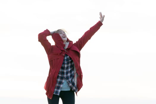 Caucasian beautiful woman stand with raise her arm up and action of happy with laughing with white sky as background.