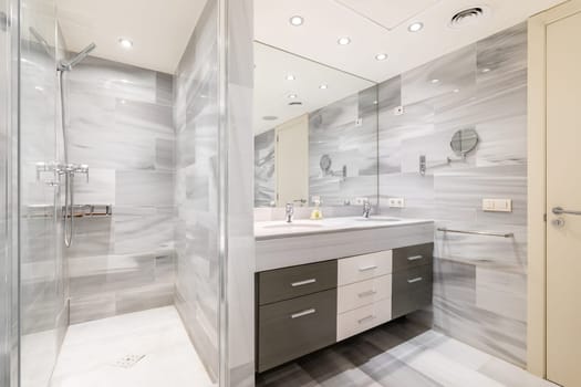 Bathroom with wall separating washbasin with vanity unit from shower area. Example of proper use of space during bathroom renovation