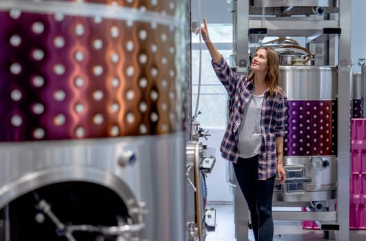 Winery worker woman walk and check the process of the machine in the modern factory with happiness.