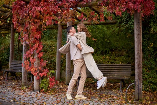 Young Cute Female Hugs Boyfriend. In Autumn Outdoor. Lovers Walking in Park. Attractive Funny Couple. Lovestory in Forest. Man and Woman. Cute Lovers in the Park. Family Concept. Happy Couple.