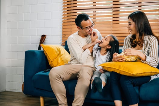 A delightful family enjoys TV and popcorn on grooved sofa fostering moments of togetherness and bonding. father mother daughter and sibling share laughter epitomizing genuine family happiness.