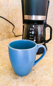 Blue coffee cups and black coffee maker from Mexico on cream background in clean kitchen.