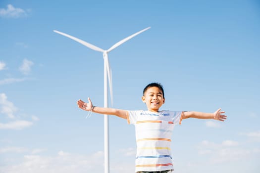 A cheerful boy enjoys the wind farm's beauty. Family fun amidst turbines signifies a playful escape to nature. The child's happiness surrounded by clean energy and windmill technology.