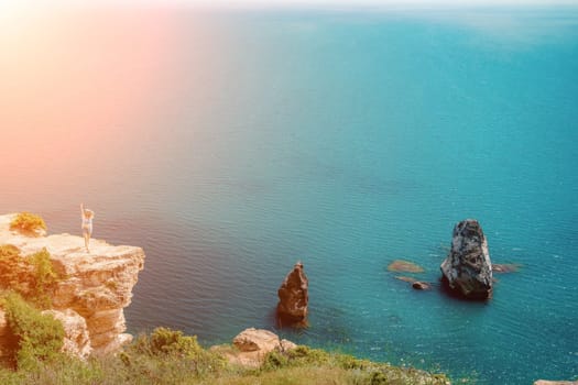 Woman travel summer sea. Portrait of a happy woman on a background of rocks and the sea. View of a woman in a white shirt and swimsuit. Freedom and happiness.