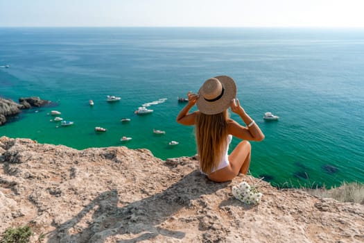 Woman travel sea. Happy woman in a beautiful location poses on a cliff high above the sea, with emerald waters and yachts in the background, while sharing her travel experiences.