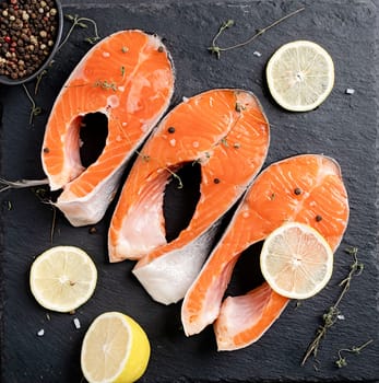 Stake Fish trout with lemon and spices on dark background with copy space