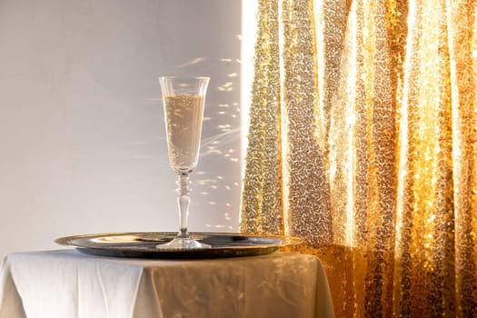 Champagne flute in tray on table against gold sparkling background