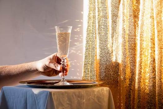 Champagne flute in tray on table against gold sparkling background