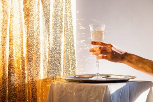 Champagne flute in tray on table against gold sparkling background