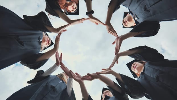 College graduates make a circle of their hands