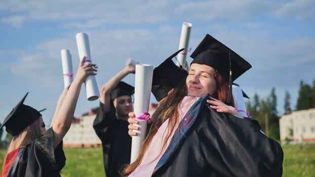 Two college graduates girls hugging on a sunny day