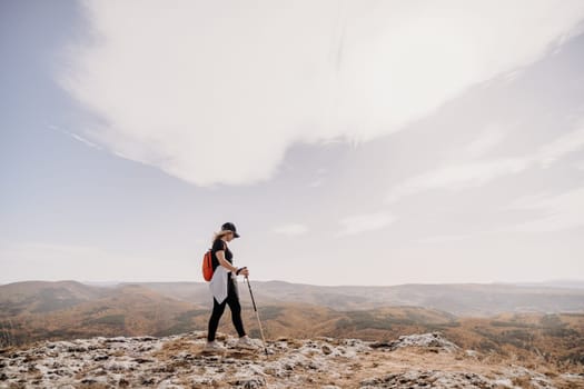 woman on mountain peak looking in beautiful mountain valley in autumn. Landscape with sporty young woman, blu sky in fall. Hiking. Nature.