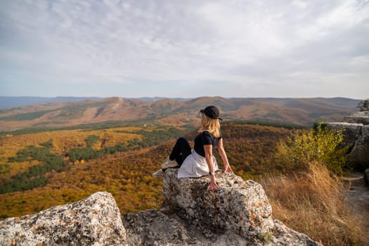 woman on mountain peak looking in beautiful mountain valley in autumn. Landscape with sporty young woman, blu sky in fall. Hiking. Nature.