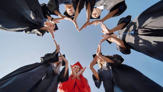 Students graduating from the college make a heart out of their hands