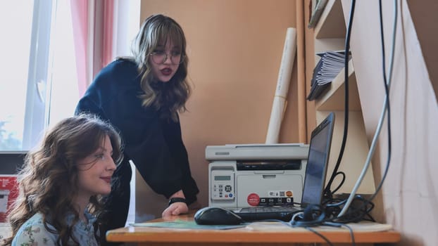 Two female students are working at a computer in a classroom at school