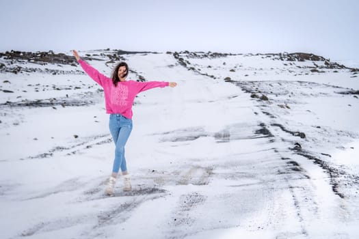 Woman in pink sweater posing on a snowy road in Iceland