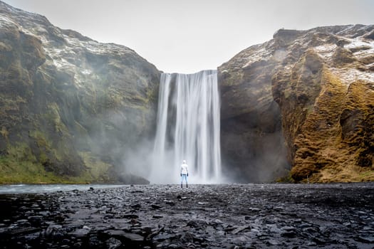 Woman with white jacket from behind in Skogafoss, Iceland