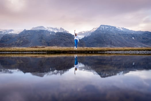 Woman posing by lake with her reflection in Iceland