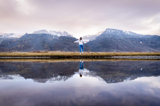 Woman posing by lake with her reflection in Iceland