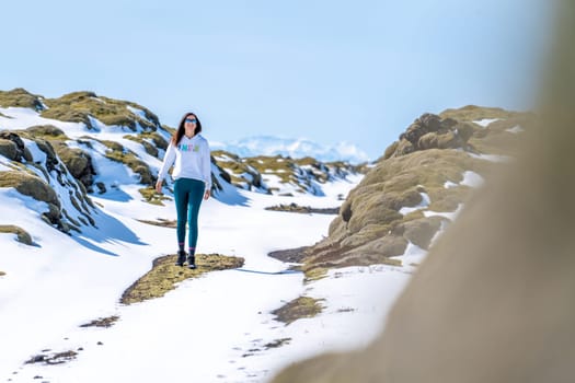 Woman walking on a snowy road on a sunny day in Iceland