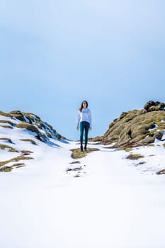 Woman with her back on a snowy road on a sunny day in Iceland