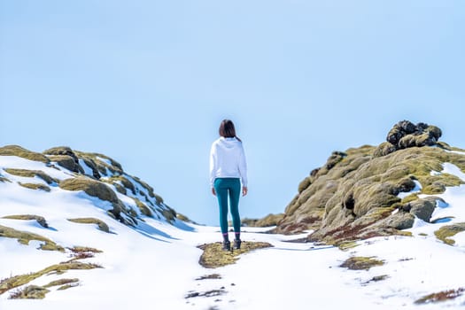 Woman with her back on a snowy road on a sunny day in Iceland