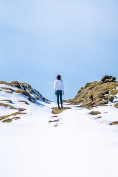 Woman with her back on a snowy road on a sunny day in Iceland