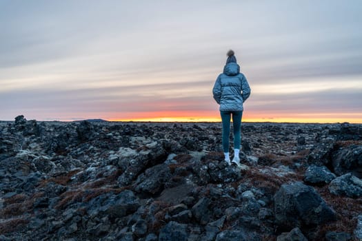 Woman posing in an ancient lava field watching sunset