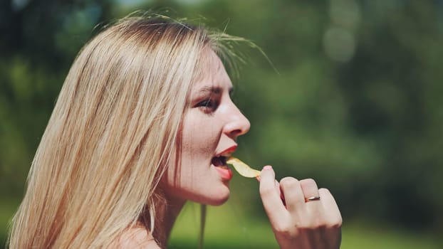 Blonde girl eating chips on the street