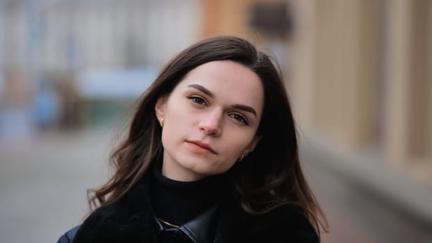 Sensitive portrait of a brunette girl on a cloudy spring day on a city street