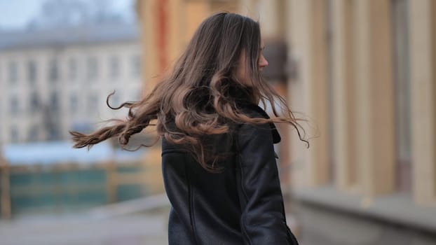 Happy brunette girl posing in black jacket in autumn in the city