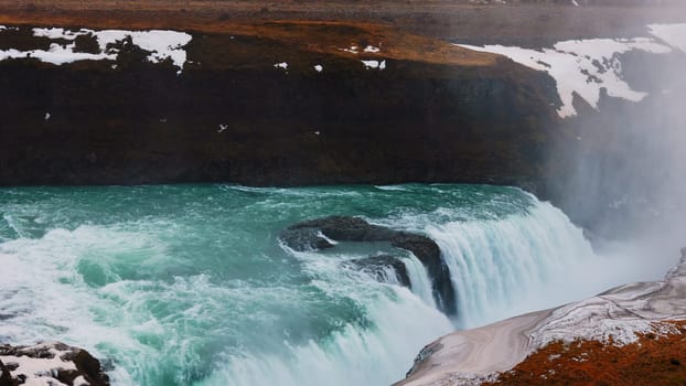 Majestic water stream in iceland with snowy nature and hills, gullfoss waterfall in reykjavik. Beautiful large river flow cascade with scandinavian nordic landscapes. Handheld shot.