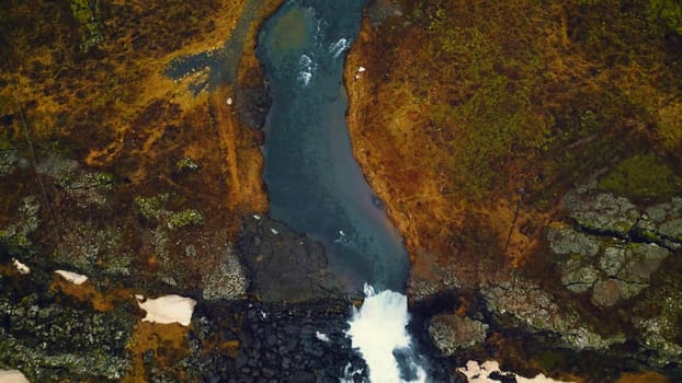 Drone shot of nordic oxarafoss waterfall in iceland, spectacular arctic scenery with huge cascade and hills. Fantastic water stream flowing down off of frozen cliffs. Slow motion.