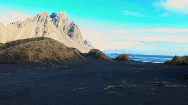 Icelandic stokksnes black sand beach with vestrahorn mountains creating spectacular scandinavian natural landscape. Beautiful ocean coastline with massive hills in iceland. Handheld shot.