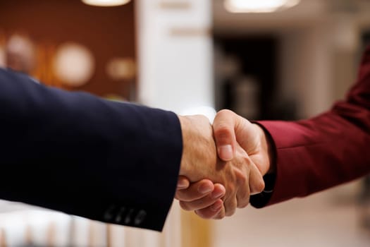 Entrepreneurs agreeing upon collab together, successful important meeting at hotel abroad. Business professionals shaking hands to mark the beginning of a fruitful partnership. Close up.